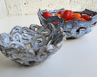 May include: Two white ceramic bowls with intricate designs. The larger bowl is filled with red and orange tomatoes.