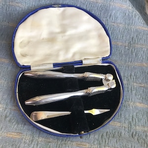 Puede incluir: Un juego de cascanueces de plata y un pincho para nueces en una caja de terciopelo azul.