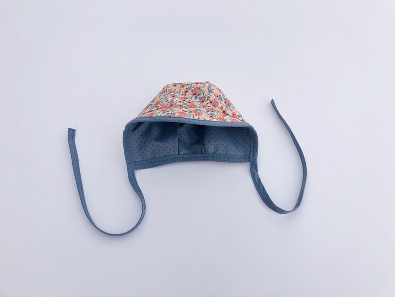 May include: A blue baby bonnet with a floral print and tie strings.