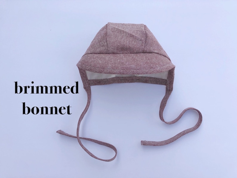 May include: A brown, brimmed bonnet with a tie. The bonnet is made of a soft, textured fabric.