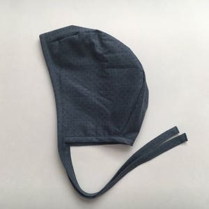 May include: A dark blue fabric surgical cap with a dotted pattern and long ties.