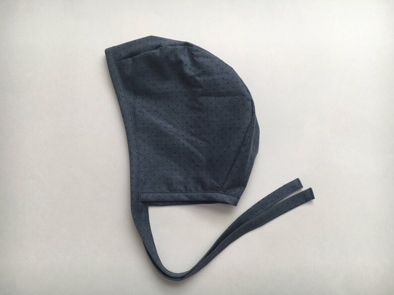 May include: A dark blue fabric surgical cap with a dotted pattern and long ties.