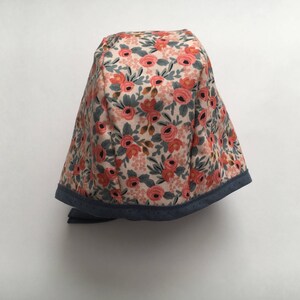 May include: A floral print fabric hat with a blue trim. The hat has a rounded shape and a tie.