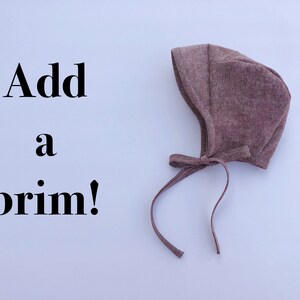 May include: A brown fabric baby bonnet with a tie. The text "Add a brim!" is written on a white background.