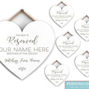 May include: Five white heart-shaped signs with the text "This seat is reserved" and a personalized name. The signs are for a wedding and are meant to be placed on chairs for guests who have passed away. The text "Watching from Heaven" is included on each sign.