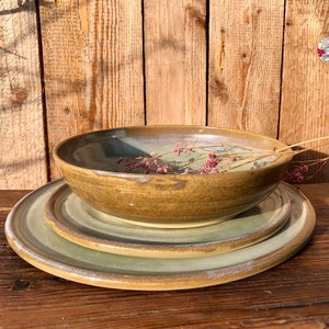 May include: A set of three ceramic dishes in shades of green and brown. The dishes are stacked on top of each other, with the largest dish on the bottom and the smallest dish on top. The dishes have a rustic, handmade look.