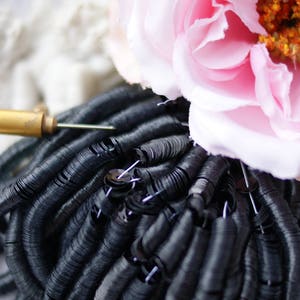 May include: A close-up of a large pile of black sequins. The sequins are arranged in a circular pattern, creating a swirling effect.