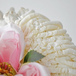 Puede incluir: Primer plano de una flor de tela rosa con lentejuelas blancas. La flor está rodeada de lentejuelas blancas.