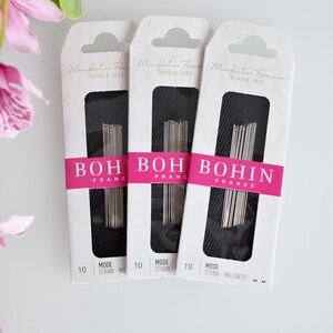 May include: Three packages of Bohin straw millinery needles. Each package is white with black text and a pink stripe. The text on the packages reads "Manufacture Fran&ccedil;aise Depuis 1833" and "Bohin France".