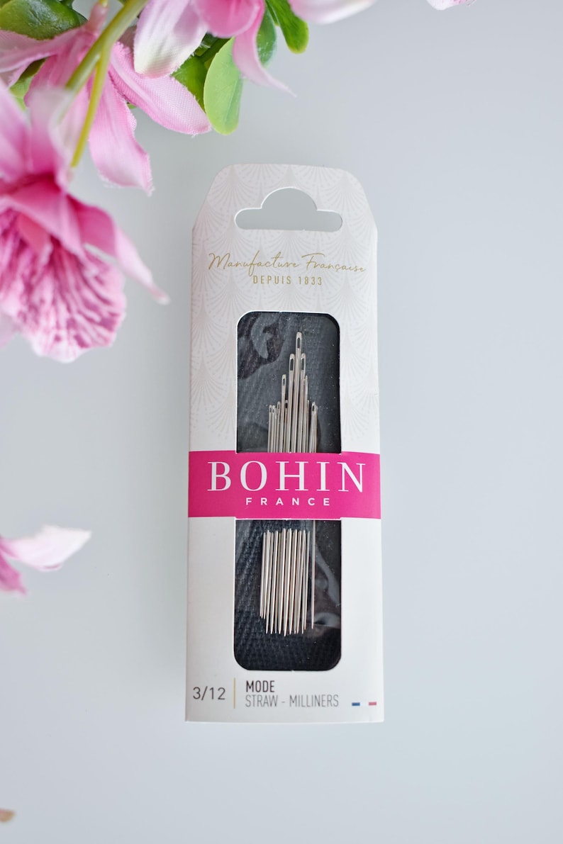May include: A package of Bohin sewing needles, size 3/12, labeled "Mode Straw - Milliners". The package is white with pink and black accents. The needles are silver and are arranged in a row.