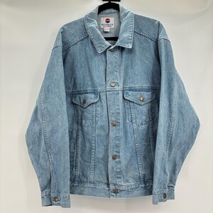 May include: Light blue denim jacket with a button-up front, two chest pockets, and two side pockets. The jacket has a collar and long sleeves. The tag on the back of the collar reads "NOTHING ELSE MATTERS PEPSI".