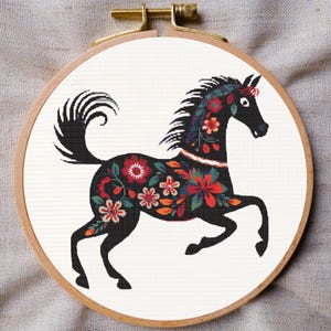 Puede incluir: Silueta negra de un caballo con un patrón floral en rojo, naranja, rosa y verde. El caballo está corriendo y tiene una cola rizada.
