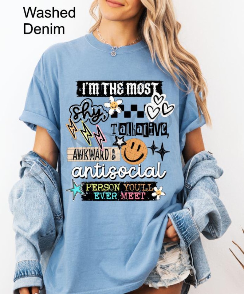 K&ouml;nnte beinhalten: Hellblaues T-Shirt mit dem Text "I'M THE MOST shy, talkative, awkward, antisocial PERSON YOU'LL EVER MEET" in verschiedenen Schriftarten und Grafiken. Das T-Shirt hat einen Washed-Denim-Look.