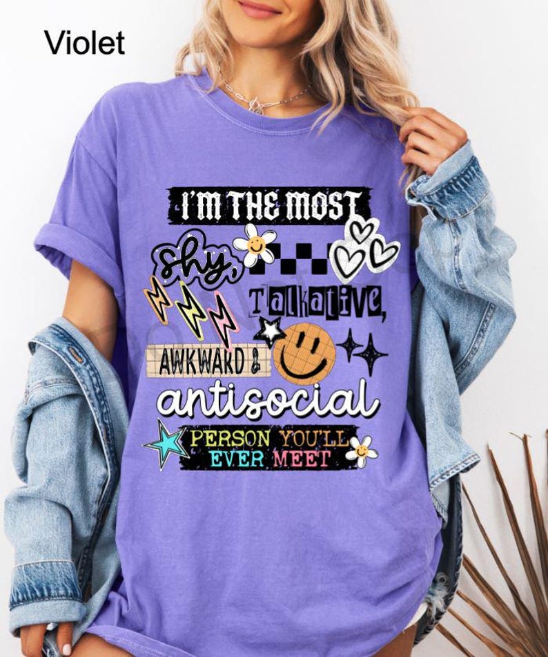 K&ouml;nnte beinhalten: Violettes T-Shirt mit dem Text "I'M THE MOST Shy, Talkative, Awkward, Antisocial PERSON YOU'LL EVER MEET" und verschiedenen Grafiken. Das Shirt hat eine lockere Passform und kurze &Auml;rmel.