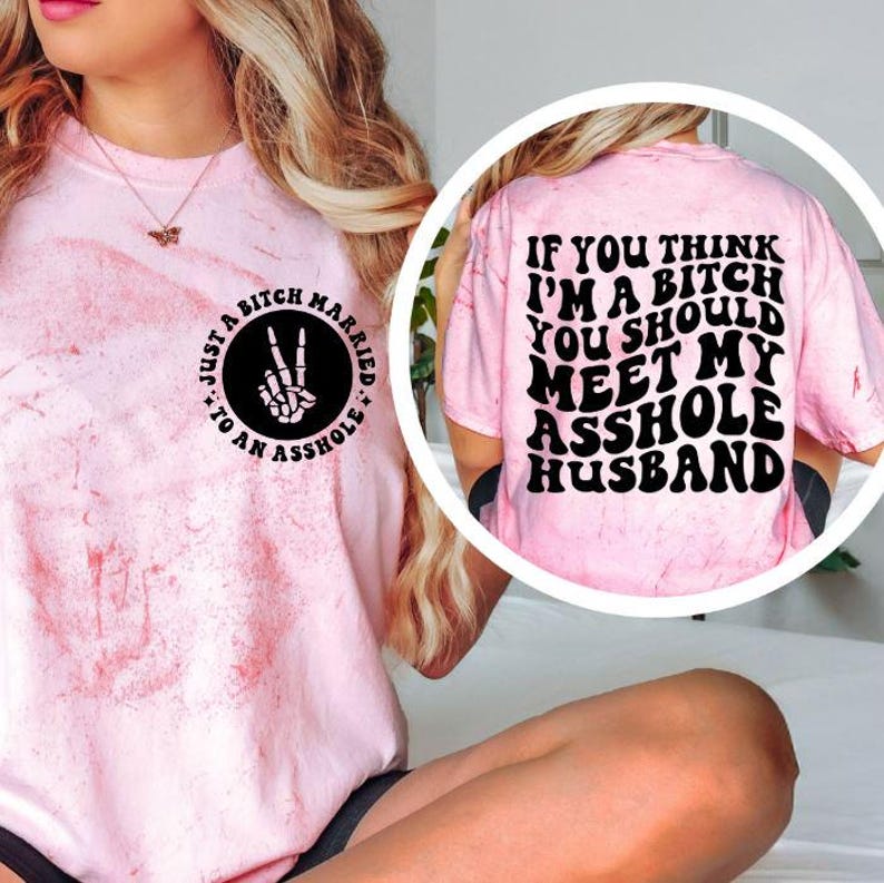 May include: Pink tie-dye t-shirt with black text on the front and back. The front reads "Just a Bitch Married to an Asshole" in a circle. The back says "If you think I'm a bitch you should meet my asshole husband."