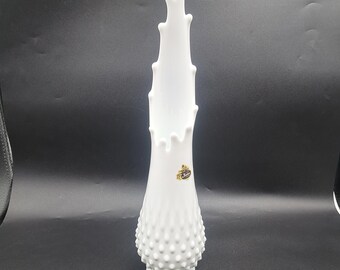 May include: White milk glass vase with a textured, dotted surface and a tall, pointed design. The vase has a label that reads "Fenton".