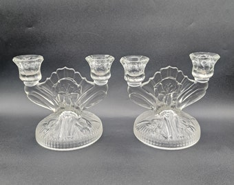 May include: A pair of clear glass candle holders with a floral design. Each holder has three candle cups.