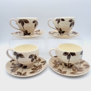 May include: Set of four brown and white teacups and saucers with a leaf pattern.