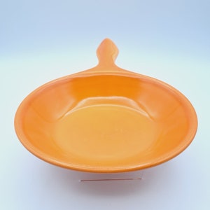 May include: Orange ceramic frying pan with a handle. The pan is empty and has a glossy finish.