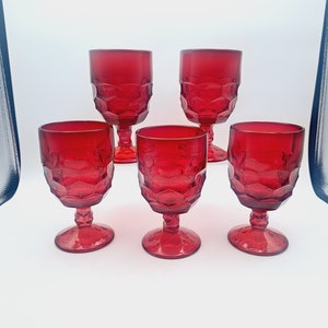 May include: Set of five red glass goblets with a diamond pattern. The goblets have a clear base and a wide bowl.