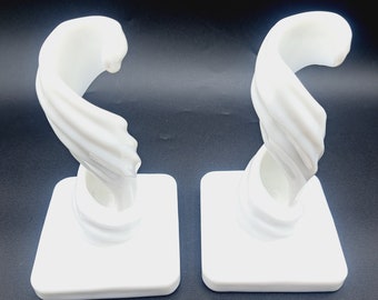 May include: Two white ceramic wall hooks with a spiral design. Each hook is mounted on a square base.
