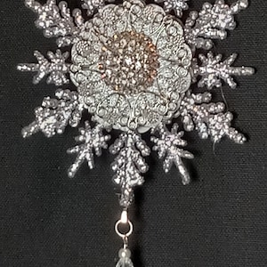Silver jeweled snowflake ornament.  Rhinestone settings embellished on two sides.