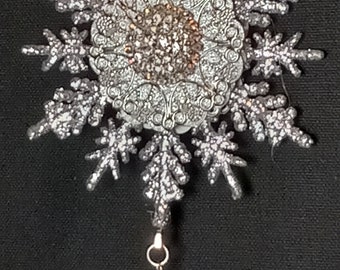 Silver jeweled snowflake ornament.  Rhinestone settings embellished on two sides.