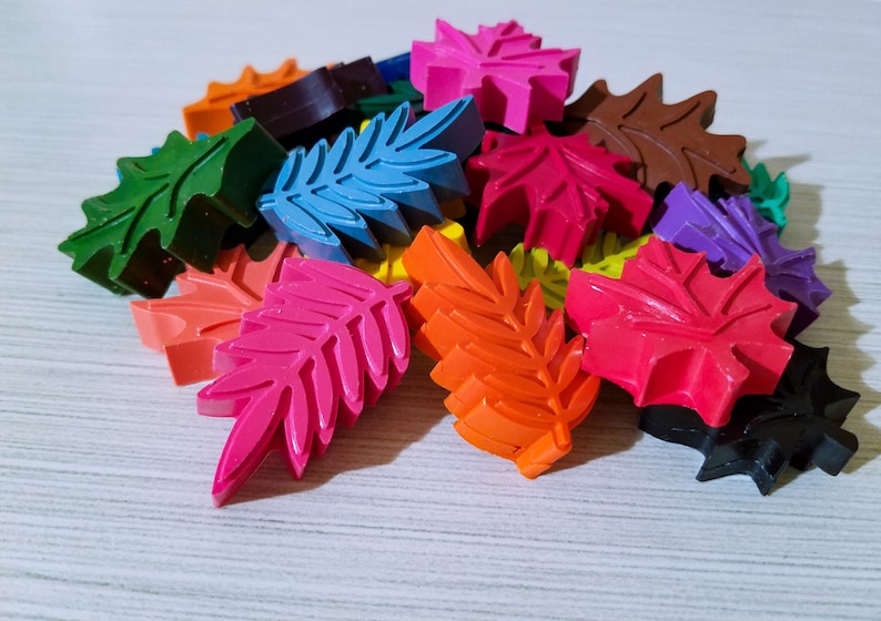 May include: A collection of colorful leaf-shaped crayons in various shades of red, orange, yellow, green, blue, purple, and black.