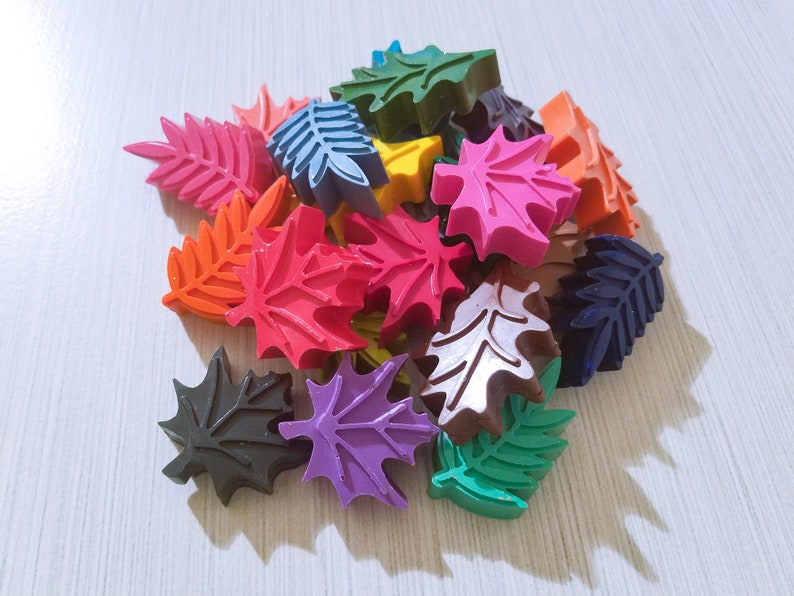 May include: A collection of colorful leaf-shaped crayons in various shades of red, orange, yellow, green, blue, purple, and brown.