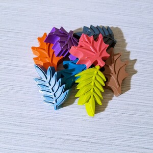 May include: A collection of colorful leaf-shaped crayons in various shades of orange, red, purple, blue, green, and brown.