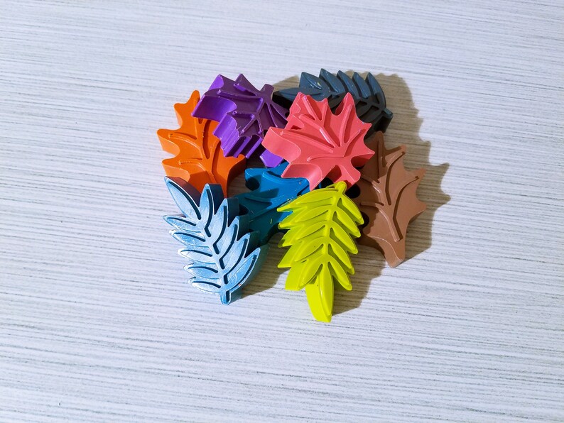 May include: A collection of colorful leaf-shaped crayons in various shades of orange, red, purple, blue, green, and brown.