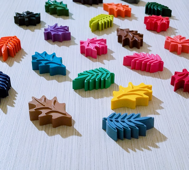 May include: Assortment of colorful leaf-shaped crayons in various shades of green, blue, red, yellow, brown, and purple.