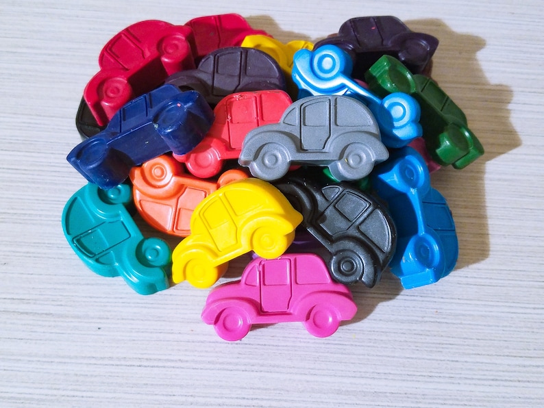 Puede incluir: Una colecci&oacute;n de coches de juguete coloridos hechos de cera. Los coches son de varios tonos de azul, verde, rojo, amarillo, rosa y negro. Los coches est&aacute;n dispuestos en una pila, con algunos de los coches superpuestos.