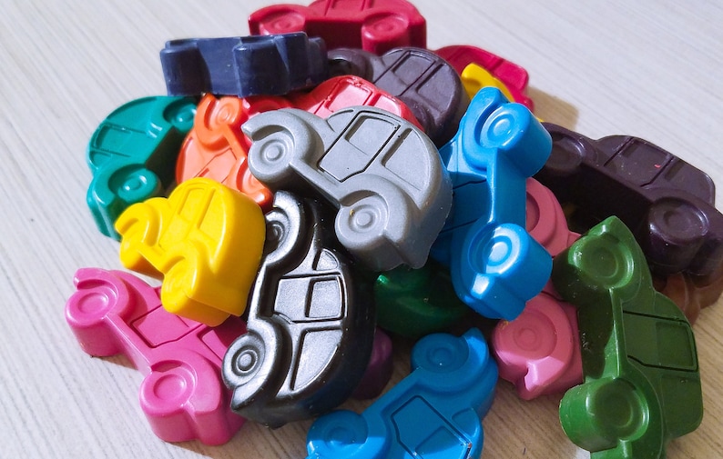 Puede incluir: Un mont&oacute;n de coches de juguete de colores hechos de cera. Los coches son de varios colores, incluyendo rojo, azul, verde, amarillo, naranja y negro. Los coches son todos de diferentes formas y tama&ntilde;os.
