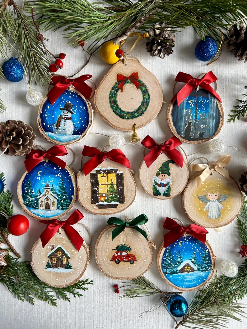 May include: Twelve unique hand-painted Christmas ornaments on wood slices.  Each slice features a different winter scene, including snowmen, churches, houses, a gnome, an angel, and a Christmas wreath.  The ornaments are adorned with red and green ribbons.  The background includes pine branches and decorative elements. rustic Christmas ornament
hand painted wood slice
winter scene ornament
handmade holiday decor