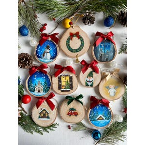 May include: Twelve hand-painted wooden ornaments with a Christmas theme. Each ornament features a different winter scene, including a snowman, a church, a window, a gnome, an angel, a house, and a car. The ornaments are decorated with red bows and are perfect for adding a touch of holiday cheer to your Christmas tree.