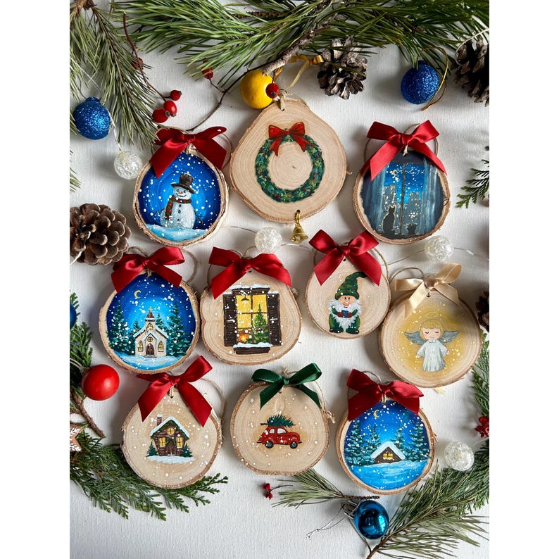 May include: Twelve hand-painted wooden ornaments with a Christmas theme. Each ornament features a different winter scene, including a snowman, a church, a window, a gnome, an angel, a house, and a car. The ornaments are decorated with red bows and are perfect for adding a touch of holiday cheer to your Christmas tree.