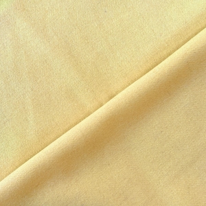 May include: A close-up of a smooth, pale yellow fabric with a subtle texture. The fabric is folded in half, creating a diagonal line across the image.
