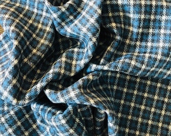 May include: Blue and white plaid fabric with a textured weave. The fabric is folded and draped, showing the pattern and texture.