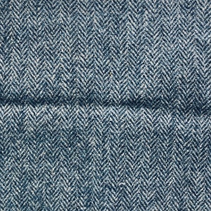 May include: Close-up of a blue and white herringbone fabric. The fabric has a subtle texture and a woven pattern.