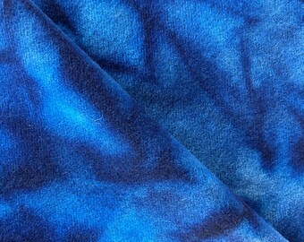 May include: Close-up of a blue and black tie-dye fabric with a soft, fuzzy texture.