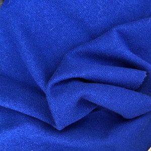 May include: A close-up of a blue fabric with a textured surface. The fabric is folded and draped, showing its soft and fuzzy texture.