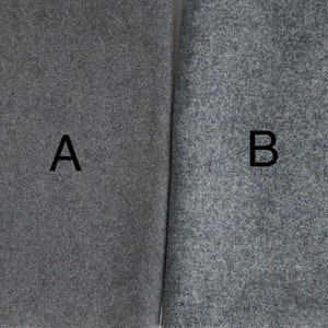 May include: Two samples of gray fabric, labeled A and B. The fabric has a textured, flecked appearance.