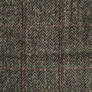 May include: A close-up of a brown, black, and green tweed fabric with a herringbone pattern. The fabric has a subtle red and white plaid pattern.