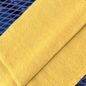 May include: A soft, yellow knitted scarf. The scarf is folded in half and the texture of the knit is visible.