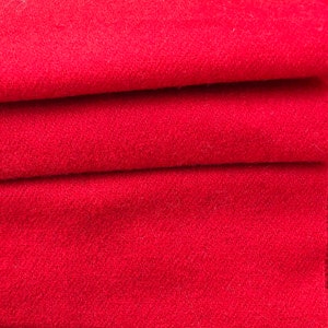May include: Close-up of a stack of red fabric. The fabric has a soft, fuzzy texture.