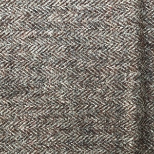 May include: A close-up of a brown and white herringbone patterned fabric. The fabric has a soft, fuzzy texture.