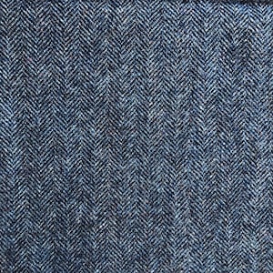 May include: Close-up of a blue herringbone tweed fabric. The fabric has a subtle texture and a classic herringbone pattern.