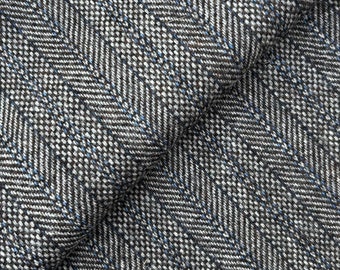 Puede incluir: Primer plano de una tela de espiga gris y negra con un sutil hilo azul que la atraviesa.