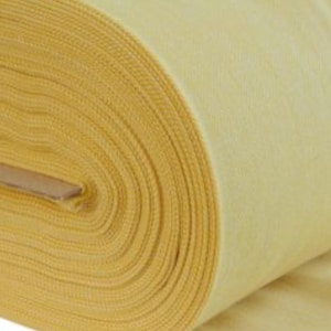 May include: A large roll of solid light yellow fabric featuring a visible woven texture. The material is tightly wound around a central cardboard core, displaying multiple layers of the textile as it spirals outward from the center point.